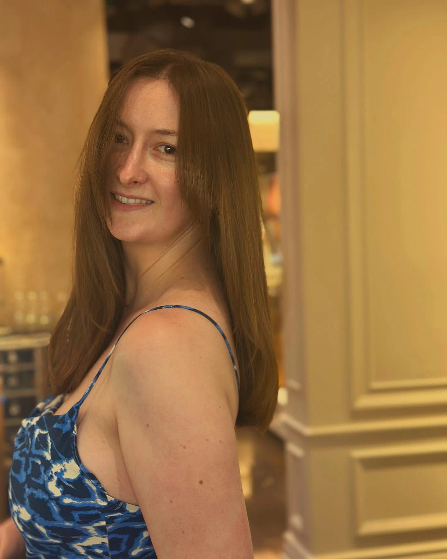 Client with long chestnut hair after a fresh cut, wearing a blue patterned dress